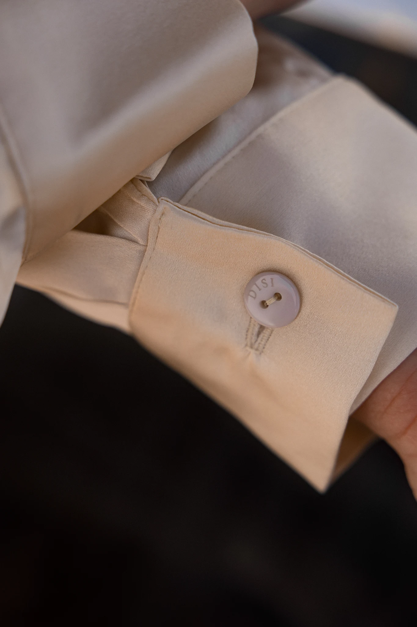 Engraved DISI button on cream silk cuff